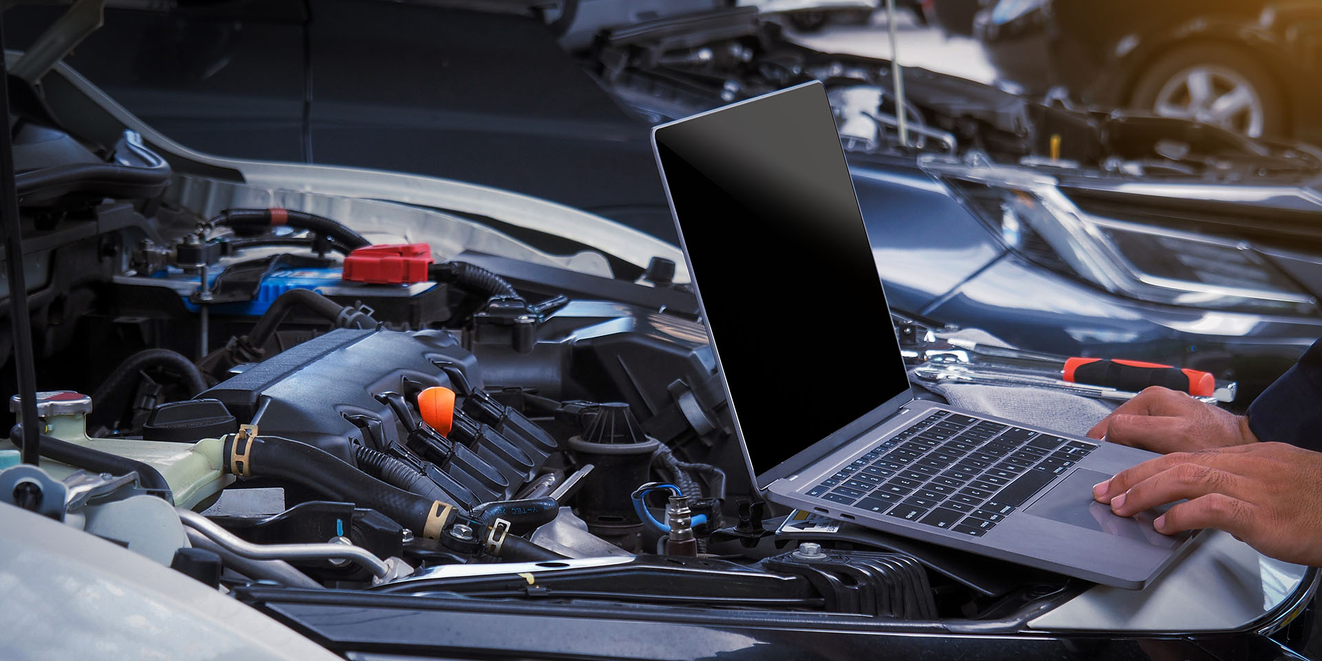 Close up hands of auto electrician using a computer laptop to di